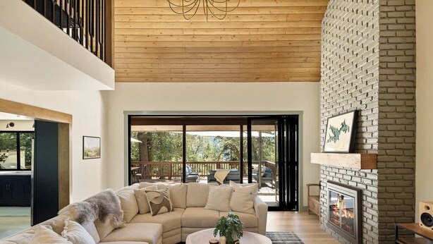 A modern living room with a sectional sofa, a fireplace, and a large window. - Geneva Pines (walk to lake!) (Lake Arrowhead)