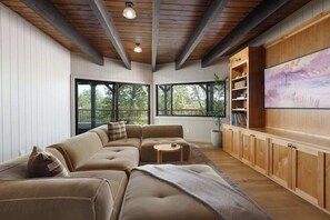 A living room with a sectional sofa, a coffee table, a TV, and wooden cabinets. - Arrowhead Overlook, w/ sauna&spa (Lake Arrowhead)