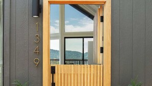 Uma porta de madeira moderna com um painel de vidro, uma caixa de correio preta e um tapete de entrada com o texto 'Kase Real Estate'.