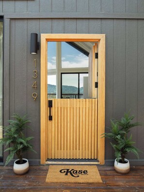 A modern wooden door with a glass panel, a black mailbox, and a doormat with 'Kase Real Estate' text. - Seven Peaks (w/ lake views, lake access!) (Lake Arrowhead)