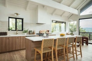 A modern kitchen with a large island, wooden bar stools, and a view of the outdoors. - Seven Peaks (w/ lake views, lake access!) (Lake Arrowhead)