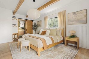A bedroom with a wooden bed, a bedside table, a hanging light fixture, a window with curtains, and a radiator. - Seven Peaks (w/ lake views, lake access!) (Lake Arrowhead)