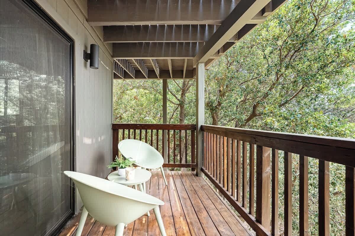 A wooden deck with a railing, a white chair, and a small table with a plant.