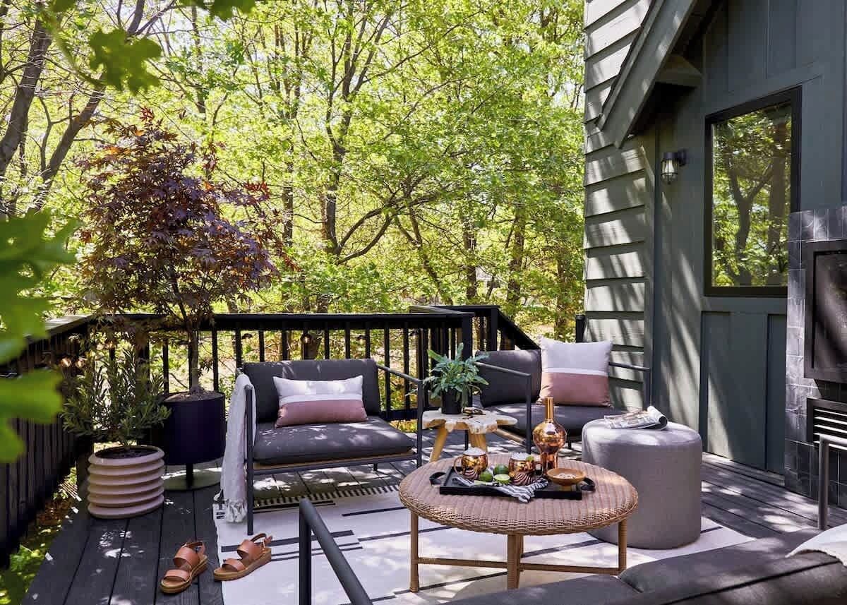 Eine Terrasse im Freien mit einer Couch, einem runden Tisch und einem Blumentopf.