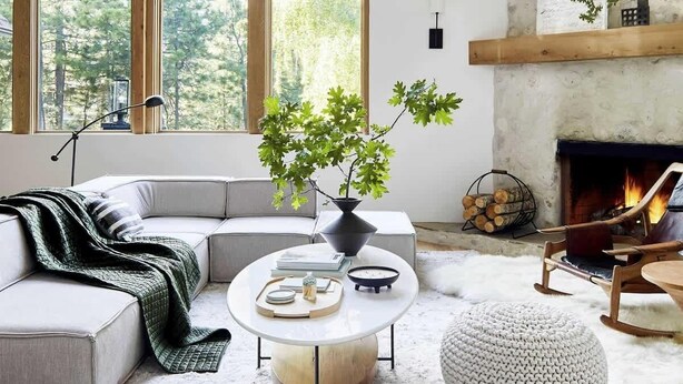 Ein modernes Wohnzimmer mit großem Fenster, Kamin, Sofa, Couchtisch und Holzboden.
