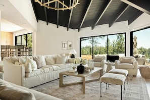 A spacious living room with a high ceiling, large windows, and a modern fireplace. - Pinnacle Point Lake House (Lake Arrowhead)