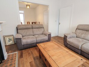 Ein Wohnzimmer mit zwei Sofas, einem Holztisch und einer Tür zu einem anderen Raum.