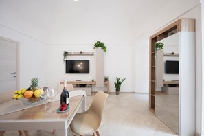 A modern dining area with a table set for two, a flat-screen TV mounted on the wall, and potted plants. - CENTRALISSIMO APPARTAMENTO COMPLETAMENTE RISTRUTTURATO NEL CUORE DI AMALFI (Amalfi)