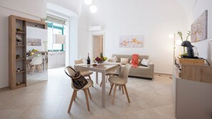 En moderne opholdsstue med spiseområde, køkken og sofa.