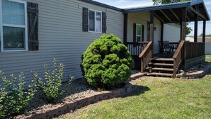 A single-story house with a covered porch, a small front yard with a well-maintained shrub, and a brick border. - Peaceful Ozark Escape Near the Artesian Well, 2BR/2BA Retreat (Marquand)