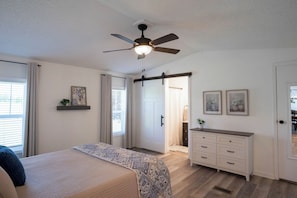 A bedroom with a bed, a ceiling fan, a dresser, and a door leading to a bathroom. - Peaceful Ozark Escape Near the Artesian Well, 2BR/2BA Retreat (Marquand)