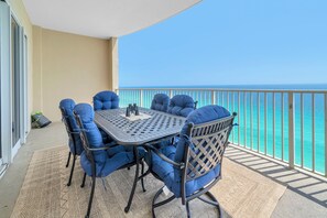 A balcony with a table and chairs, a view of the ocean, and a railing. - 🦞Gulf Front | Beach Service | Pool | 2BR Ocean Villa 2101🌅 (Panama City Beach)