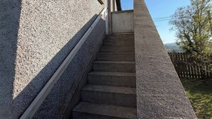 Una escalera que lleva a un edificio con una pared exterior texturizada y una ventana pequeña.
