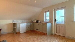 Una cocina amplia con piso de madera, microondas integrado y refrigerador.