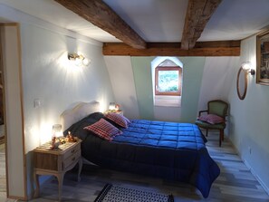 Ein Schlafzimmer mit einem Bett, Nachttischlampen, einem Sessel, einem Fenster und einem Bild.