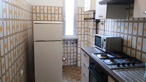 A compact kitchen with a refrigerator, microwave, stove, and tiled walls. - RG019 - Bellaria, bright three-room apartment 100 meters from the sea (Bellaria-Igea Marina)