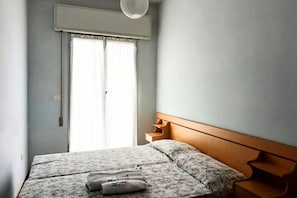 Una camera da letto con un letto, una finestra con tende e un condizionatore d'aria a parete.