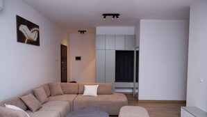 A modern living room with a sectional sofa, a round coffee table, and a TV. - Modern 110 sqm apartment near Tirana and airport (Valias)