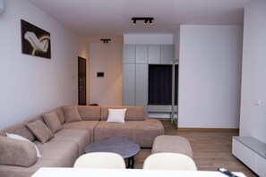 A modern living room with a sectional sofa, a round coffee table, and a TV. - Modern 110 sqm apartment near Tirana and airport (Valias)