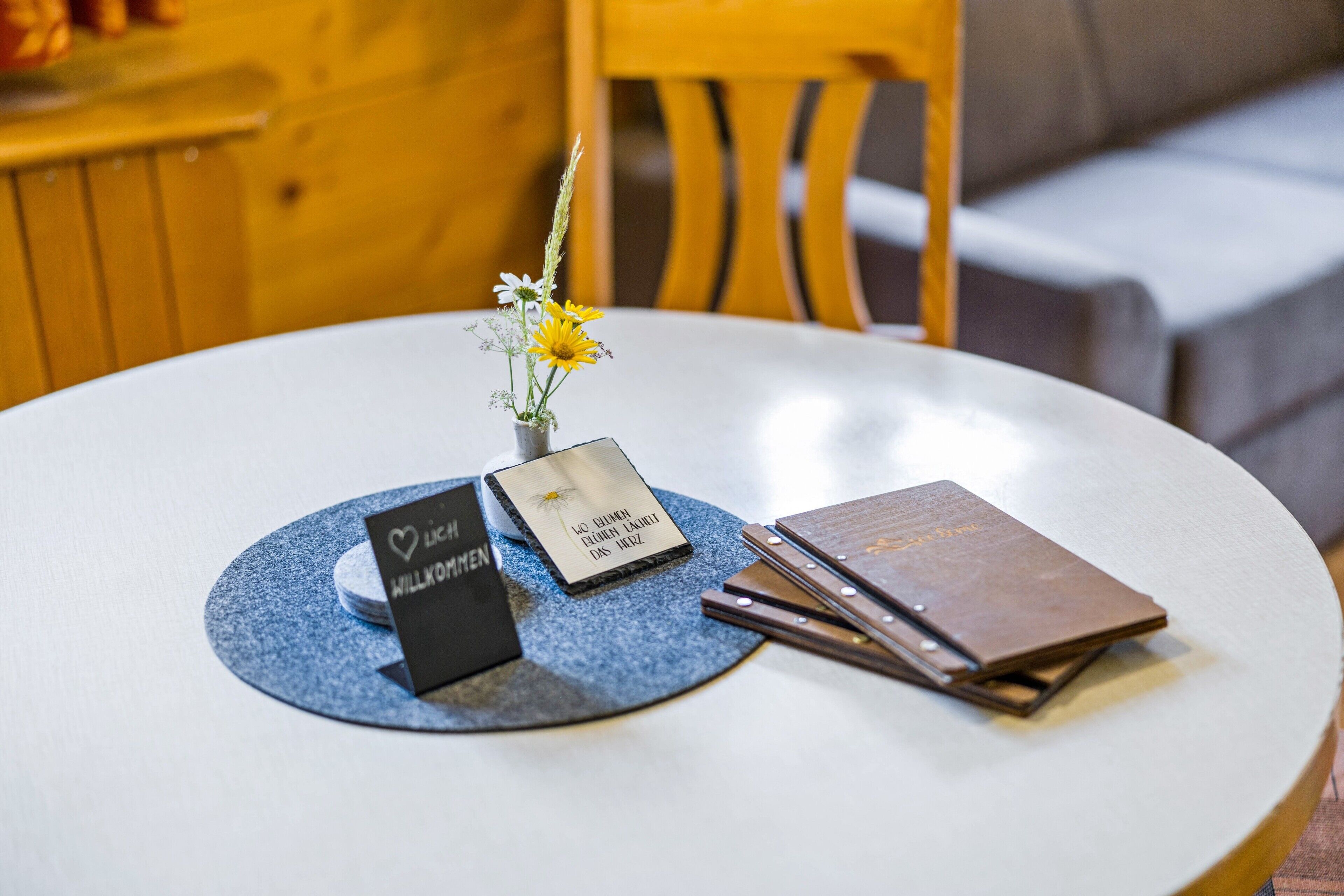 A round table with a name card, a small vase with flowers, and a stack of books.