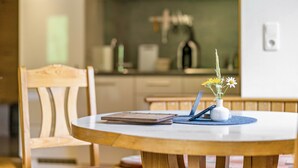 Une table  à manger avec un ordinateur portable, un carnet et un vase rempli de fleurs.