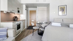 Ein modernes Hotelzimmer mit einer Küchenzeile, einem Essbereich und einem Bett.