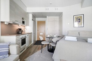 Ein modernes Hotelzimmer mit einer Küchenzeile, einem Essbereich und einem Bett.