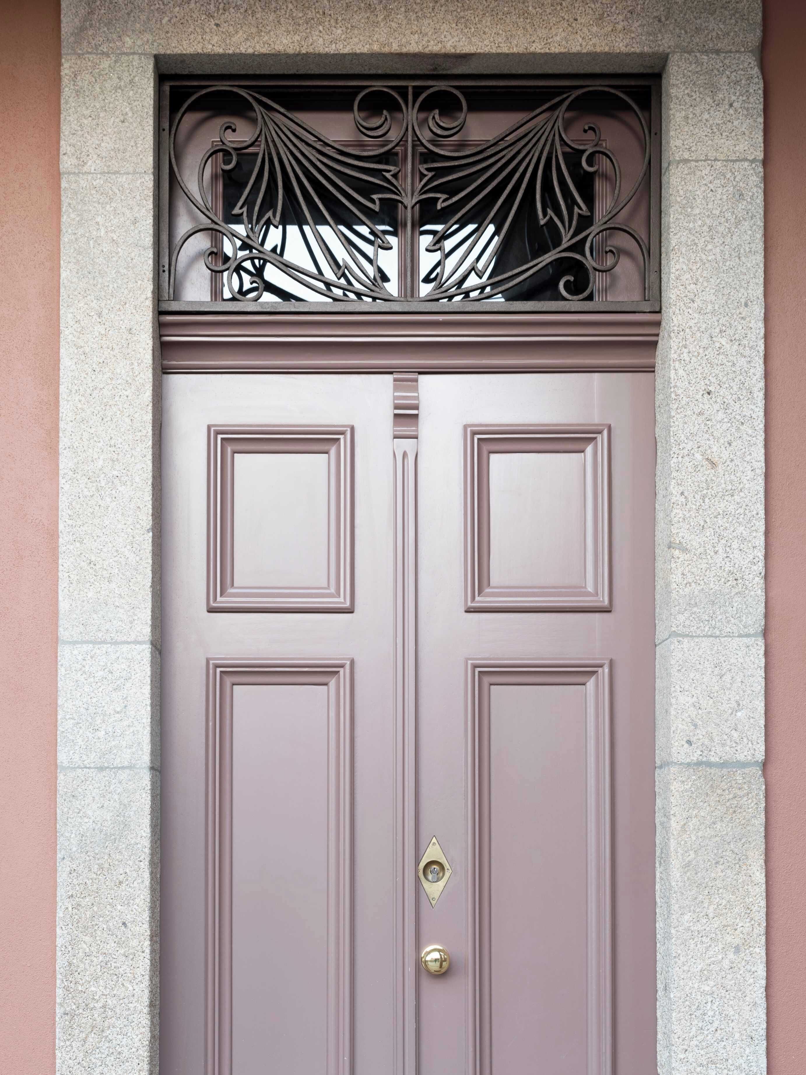A double door with a decorative metal grille above it, set in a stone wall.