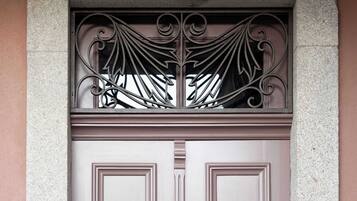 A double door with a decorative metal grille above it, set in a stone wall.