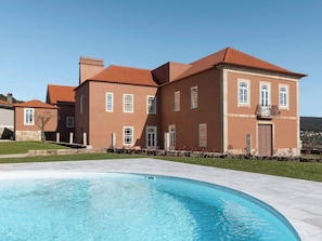 Un edifici gran de dos pisos amb una piscina al primer terme.