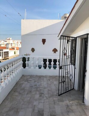 Ein Balkon mit weißer Reling, Fliesenboden und Wanddekoration.