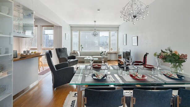 A modern living space with a glass dining table, chairs, a sofa, and a kitchen area with glass cabinets. - Aurora City Apartment 3bdr By Lapland Host (Rovaniemi)