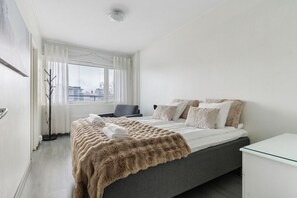 A modern hotel room with a bed, a desk, and a view of the city. - City Center Apartment Free Parking By Lapland Host (Rovaniemi)