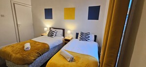 Two single beds with headboards, bedside tables with lamps, and a door. - OG Stays VII- Free Parking & Wifi, Near stadium, Nissan & Royal hospital (Sunderland)