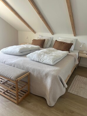 A bedroom with a bed, pillows, bedside tables, a lamp, and a wooden bench. - Modern vacation home with large garden just 1.5 km from the beach (Julianadorp)