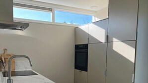 Una cocina moderna con horno integrado, un lavamanos y una ventana sobre la encimera.