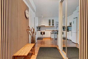 Una cocina moderna con armarios blancos, un banco de madera y un reloj en la pared.