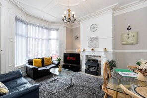 Ein Wohnzimmer mit Kamin, Fernseher und Glastisch.