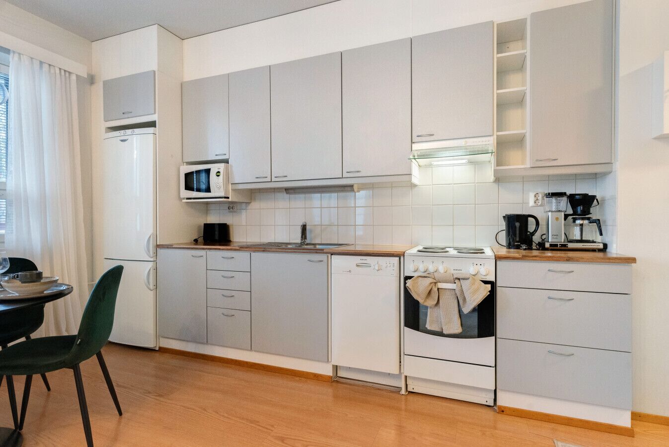 Una cocina moderna con armarios blancos, microondas, estufa y cafetera.