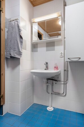 Un bagno con lavandino bianco, specchio e pavimento piastrellato di blu.