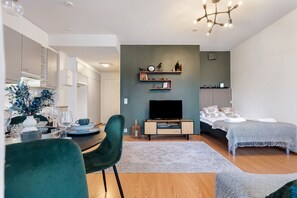 Een moderne woonkamer met een televisie, bank en eethoek.
