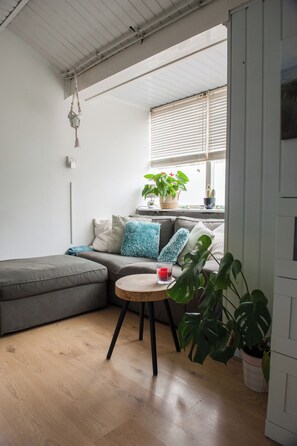 Una sala de estar moderna con un sofá seccional gris, una mesa redonda de madera y una planta en maceta.