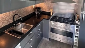 Une cuisine moderne avec des meubles de couleur sombre, une cuisinière en acier inoxydable et un plan de travail en granit.