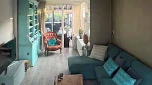 Un salon avec un canapé turquoise, une table basse en bois, un fauteuil rouge et un meuble turquoise.