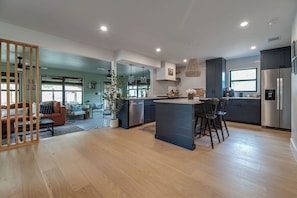 A spacious kitchen with a central island, modern appliances, and a view to the living area. - Designer Luxury 3BR with Pool and Hot Tub, Walk to Main St (Fredericksburg)