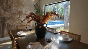 A dining table with a vase of autumn leaves, wine glasses, and plates. - Designer Luxury 3BR with Pool and Hot Tub, Walk to Main St (Fredericksburg)