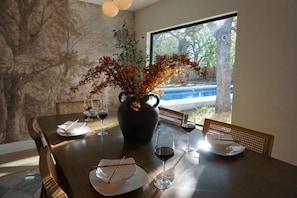 A dining table with a vase of autumn leaves, wine glasses, and plates. - Designer Luxury 3BR with Pool and Hot Tub, Walk to Main St (Fredericksburg)