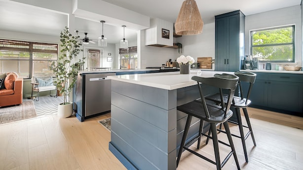 A modern kitchen with a large island, bar stools, pendant lighting, and a view of the outdoors. - Designer Luxury 3BR with Pool and Hot Tub, Walk to Main St (Fredericksburg)