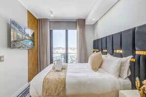 Et hotelværelse med en stor seng, et fjernsyn ophængt på væggen og udsigt over byen gennem vinduet.