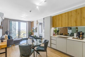 A modern apartment with a dining area, kitchen, and large windows offering a city view. - Ellipse Guest House Close to Mall of Africa (Johannesburg)